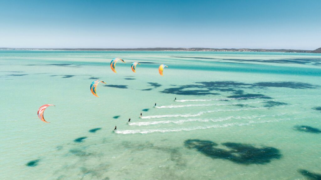 Kite surfer riding across turquoise water on a sunny beach holiday